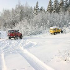 Kaksi maastoautoa lumisella aukiolla